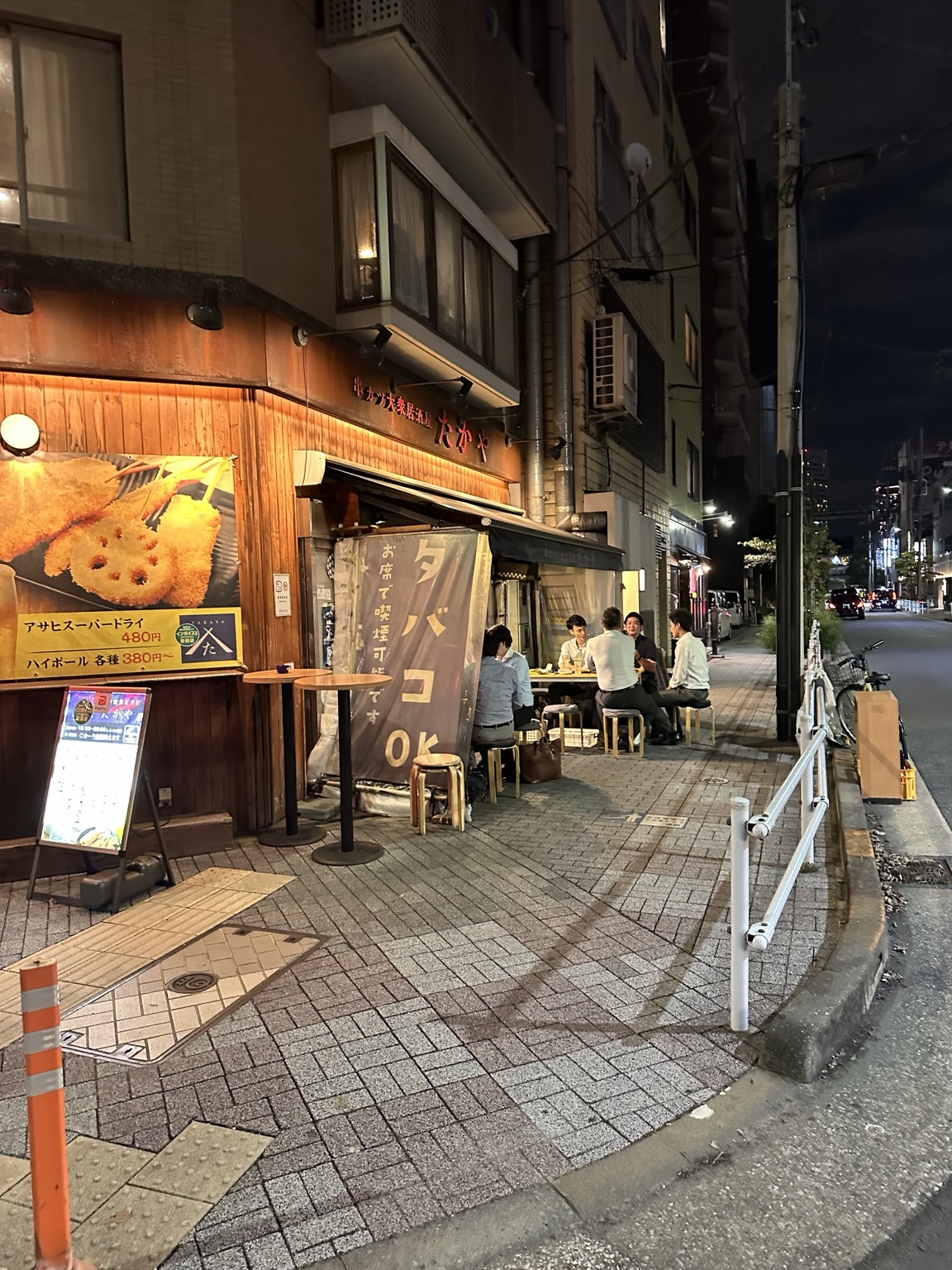 A neighborhood izakaya in Tokyo at night with local diners seated outside